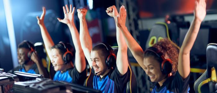 Uśmiechnięci młodzi ludzie z uniesionymi rękami w ramach zwycięstwa. 